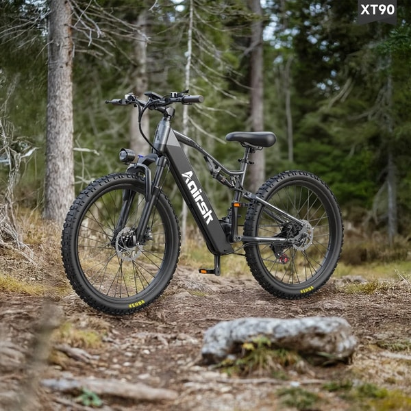 Zwarte Aairsk XT90 elektrische mountainbike getoond op een bospad met volledige vering, voorste koplamp en brede off-road banden