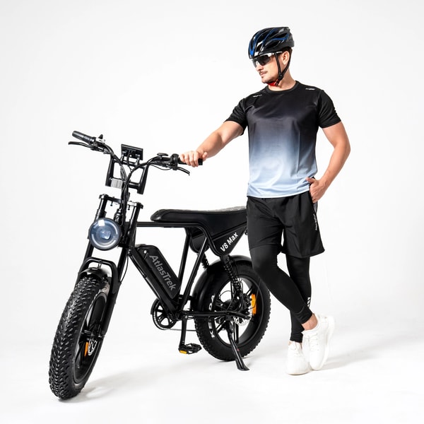 Man staand naast een zwarte AtlasTrek V8 Max elektrische fatbike in een studio-omgeving