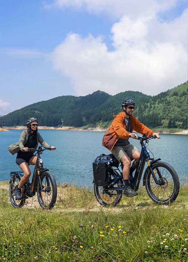 Twee rijders met helm op Engwe E26 3.0 Pro elektrische fietsen naast een bergmeer