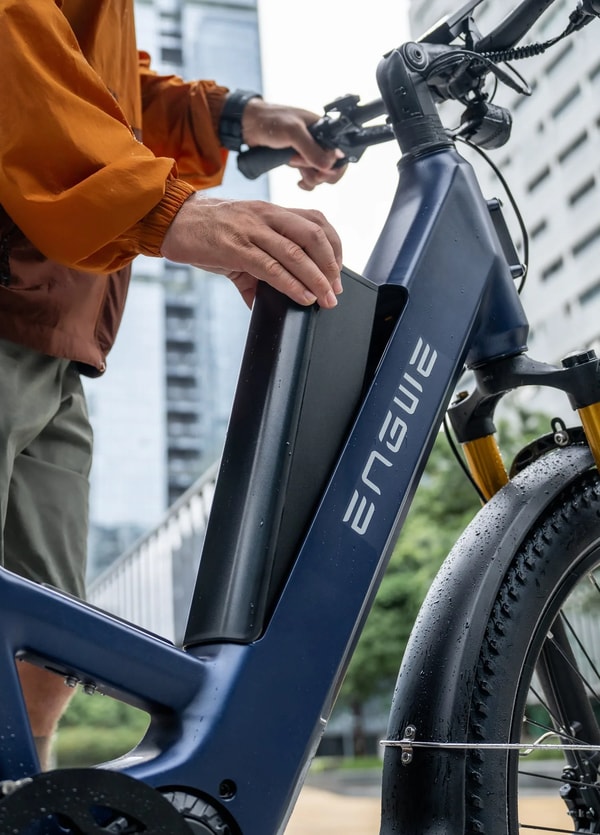 Rijder die de geïntegreerde accu uit het frame van de blauwe Engwe E26 3.0 Pro elektrische fiets haalt