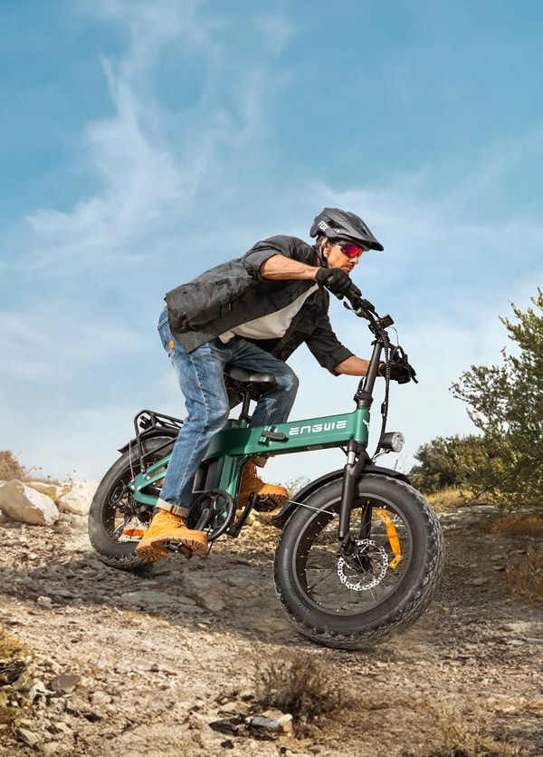 Engwe EP-2 3.0 Boost rider wearing a helmet and protective clothing while riding the green electric fat bike over rocky off-road terrain