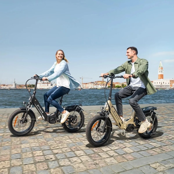 Twee rijders die langs een waterkantpromenade reizen op zwarte en champagne gouden Engwe L20 3.0 Pro elektrische fietsen