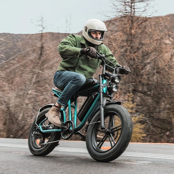 Rijder met helm die op een groene Engwe M20 elektrische fatbike op een weg rijdt met brede banden en dubbele koplampen