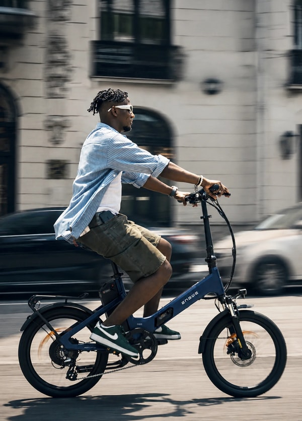 Rijder met zonnebril die een blauwe Engwe O20 Boost opvouwbare elektrische fiets door een stadsstraat rijdt